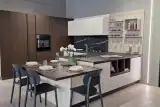 Cucina AR-DUE Q01 ad angolo con penisola e tavolo snack, colonne effetto legno e top effetto marmo nero, vista d'insieme