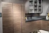 Colonne in olmo scuro della cucina AR-TRE Up Design con pensili a vetrina dal telaio nero illuminati a LED, lavello e top in Fenix nero