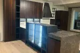 Cucina Glamour con isola scura vista laterale e vetrina illuminata