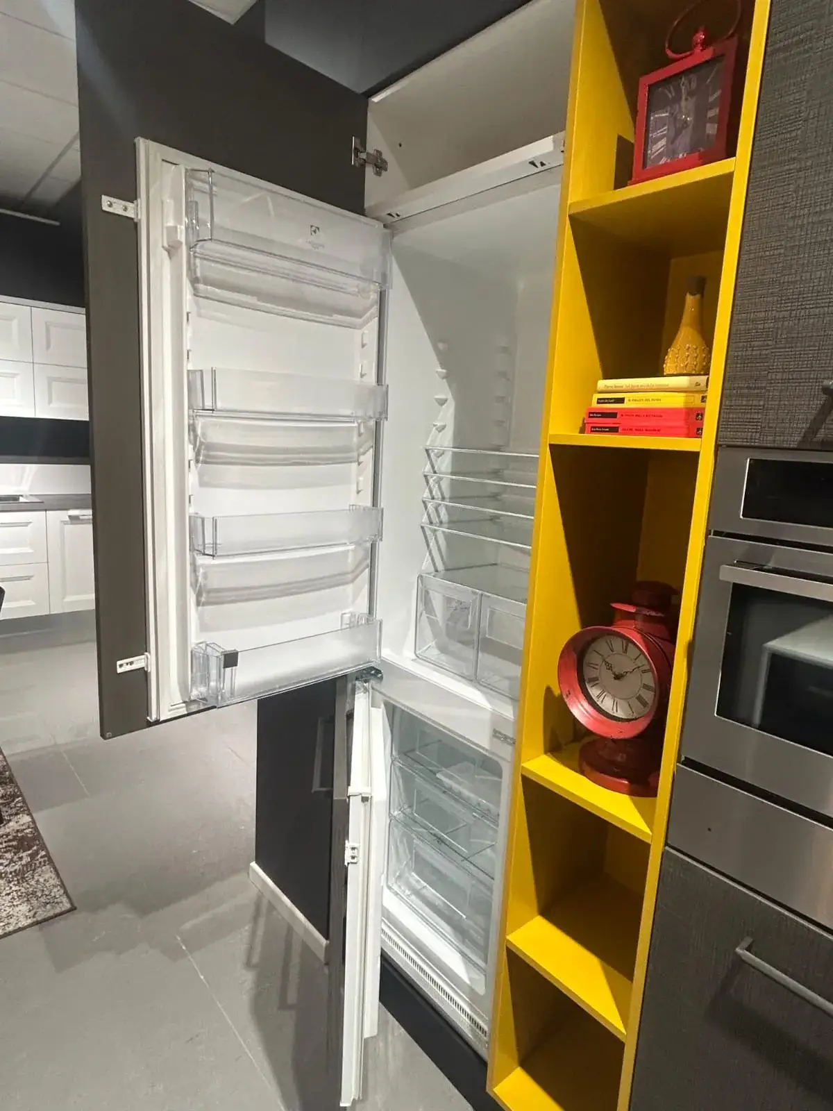 Colonna con frigorifero integrato Electrolux e libreria gialla a giorno