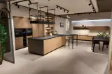 Cucina Prima Gola Linear con isola in laccato pesca opaco e top in gres nero, parete di colonne in gessato noce, penisola snack, tavolo e sedie — vista d'insieme