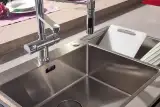 Lavello Franke in acciaio inox con miscelatore a molla sul piano in Neolith Pietra Luna dell'isola Aliant, accanto al piano cottura a induzione