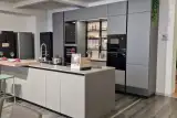 Cucina Stosa Metropolis in PET Grigio con isola Aliant in Neolith Pietra Luna e piano snack in effetto noce, vista d'insieme della composizione